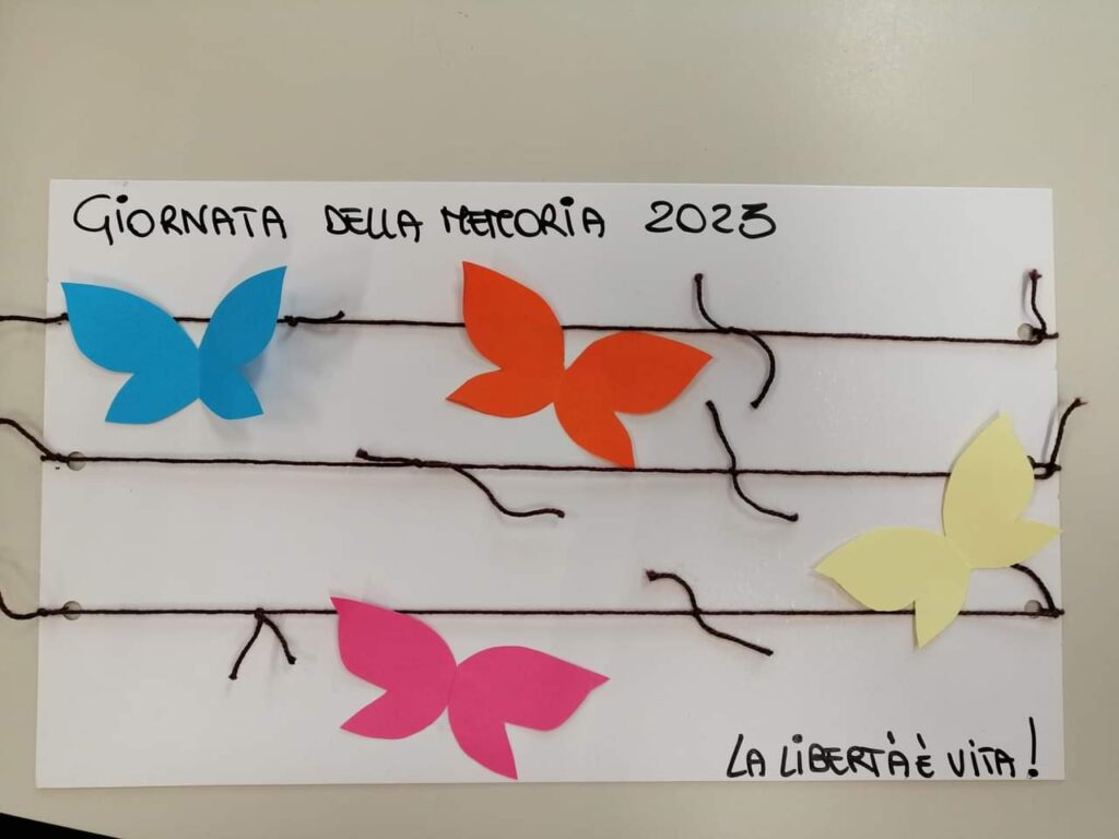 Immagine di farfalle colorate attaccate su un foglio con del filo di lana nero per rappresentare la giornata della memoria  